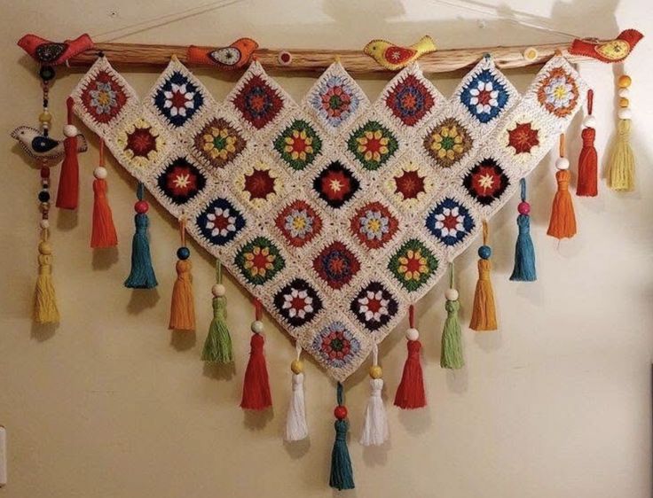 Painel decorativo de crochê colorido com franjas e detalhes de pássaros em madeira