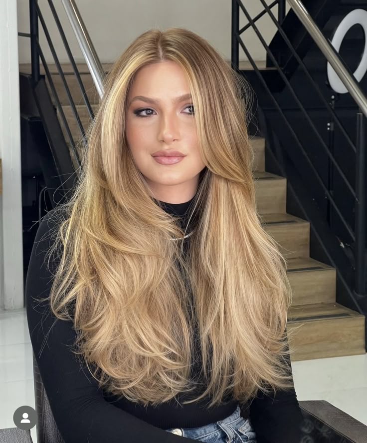 Mulher com cabelo loiro amanteigado, em tom dourado e suave, com fios volumosos e bem cuidados.