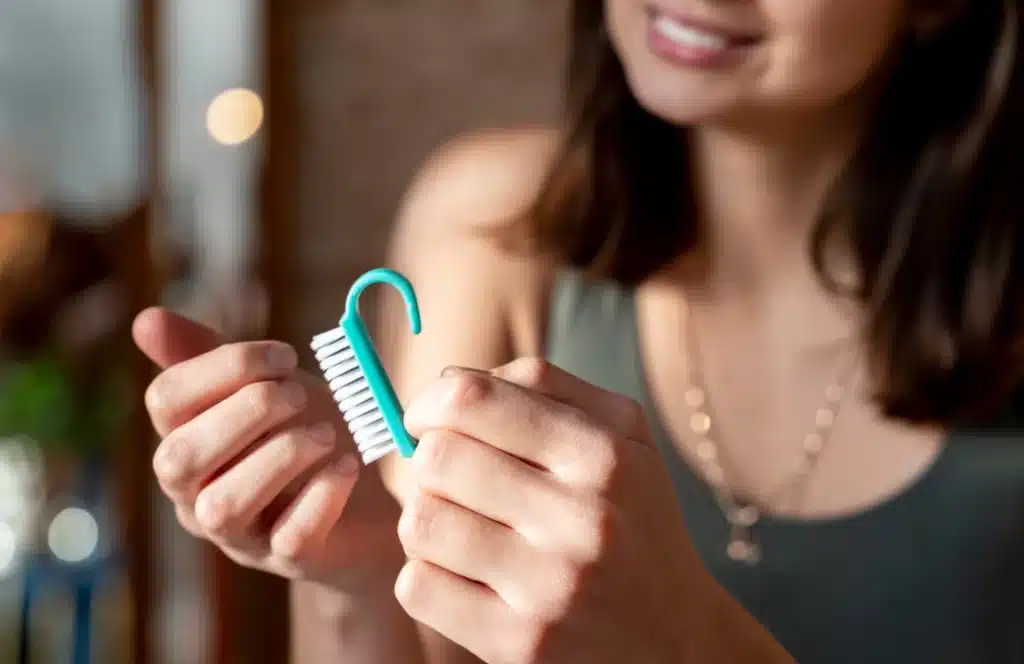 Pessoa segurando escovinha de unha durante preparação para esmaltação