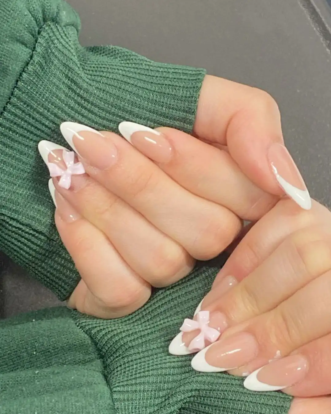 Unhas com francesinha branca e laço rosa aplicado como decoração