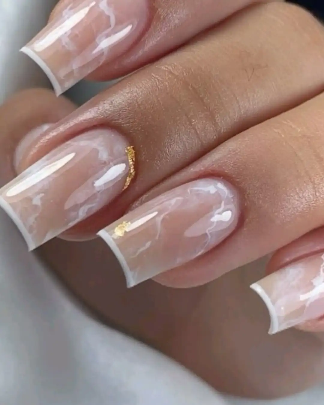 Unhas com francesinha branca, efeito marmorizado e detalhe em ouro