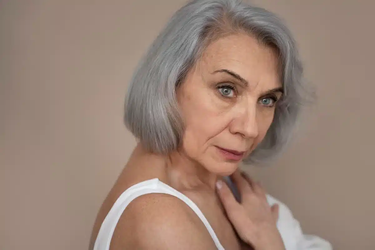 Mulher com cabelo grisalho em estilo moderno, refletindo a tendência da moda dos grisalhos, aos 50 anos.