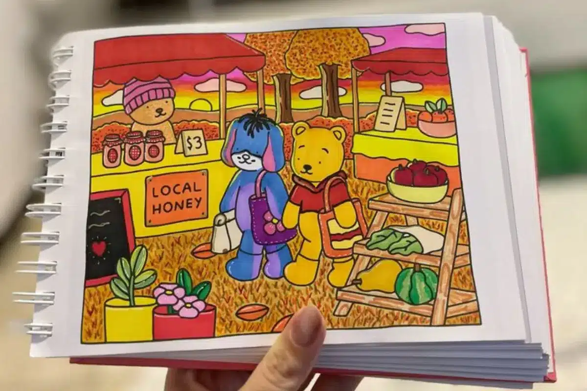 Ilustração colorida de dois personagens de pelúcia, um urso e um cachorro, em um mercado ao ar livre com barracas de mel e frutas. Eles estão caminhando por entre flores e vegetação no outono.
