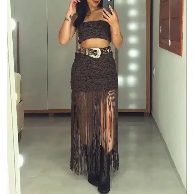 Mulher com saia de crochê marrom com franjas e bota em look de festa
