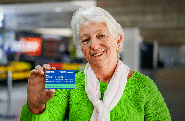 Idosa segurando o Cartão do Idoso com sorriso no rosto