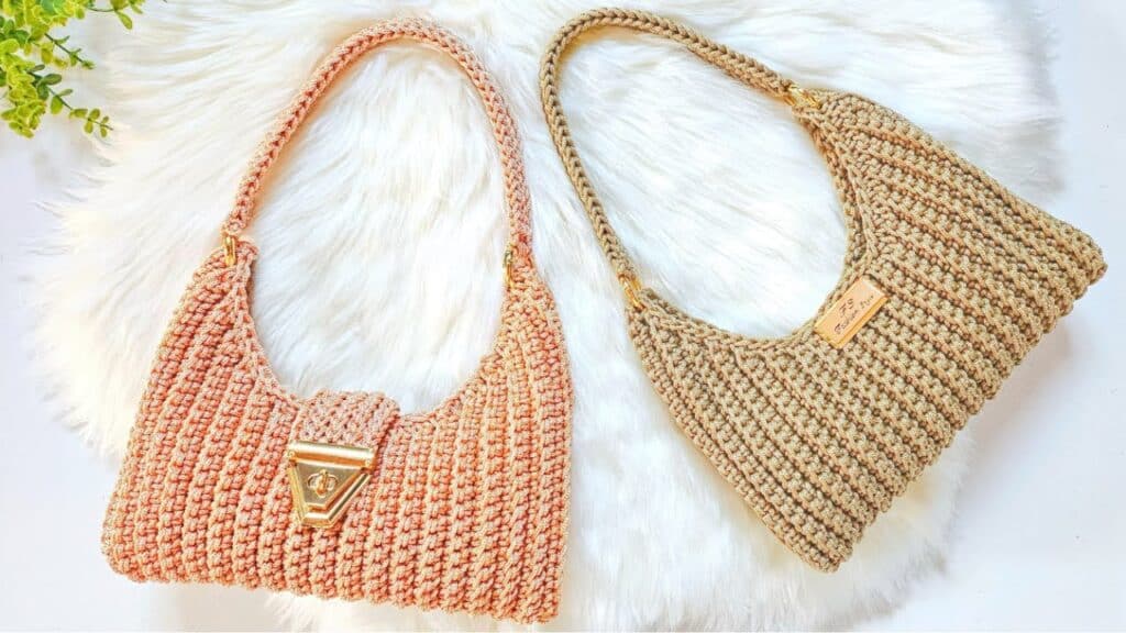 Bolsa baguete de crochê nas cores rosa e bege, com fecho dourado e alça trançada.