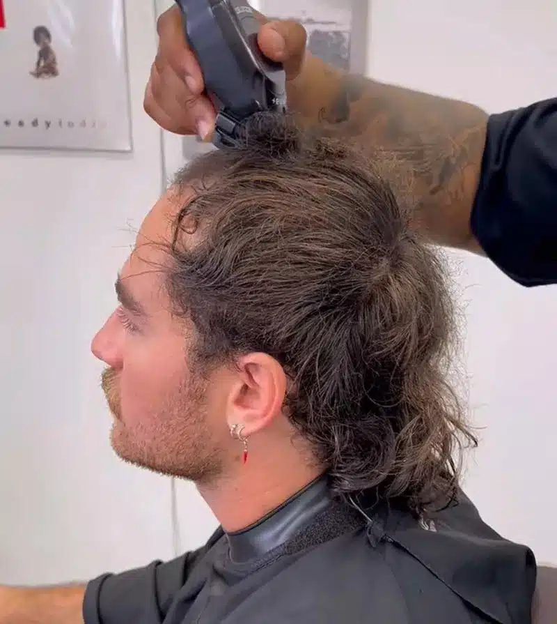 Barbeiro cortando cabelo em estilo meio calvo, tendência masculina para 2025.
