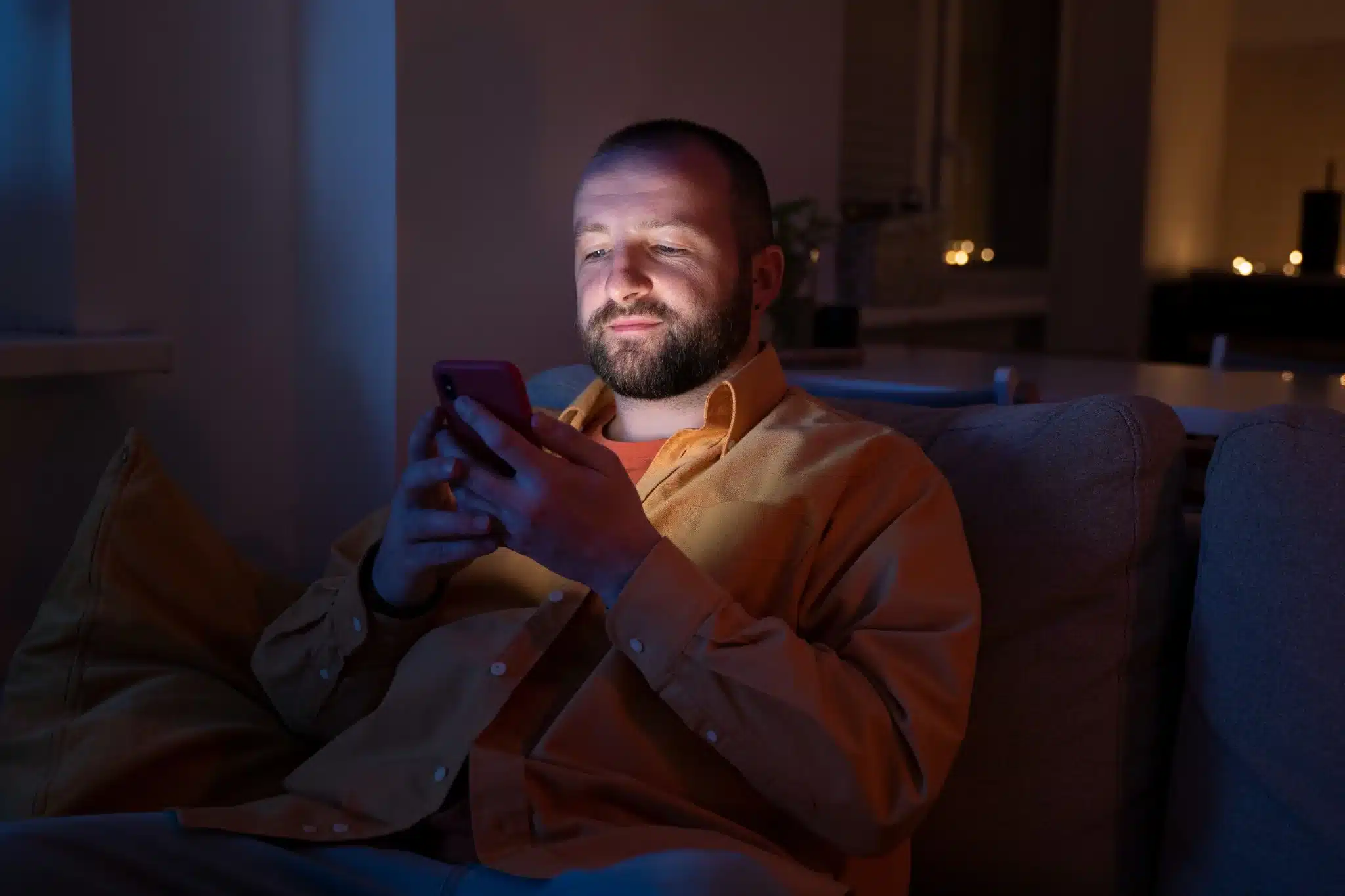 Homem enviando mensagem de boa noite pelo celular antes de dormir