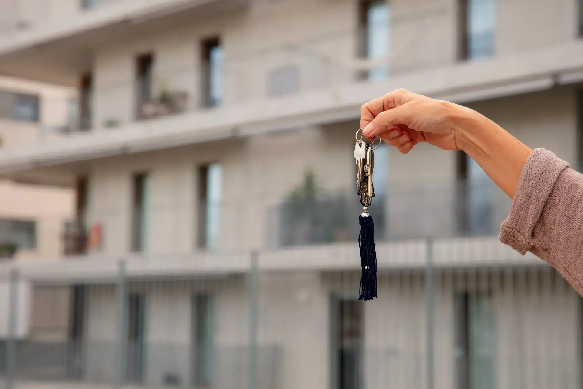 Pessoa segurando chaves diante de um prédio.