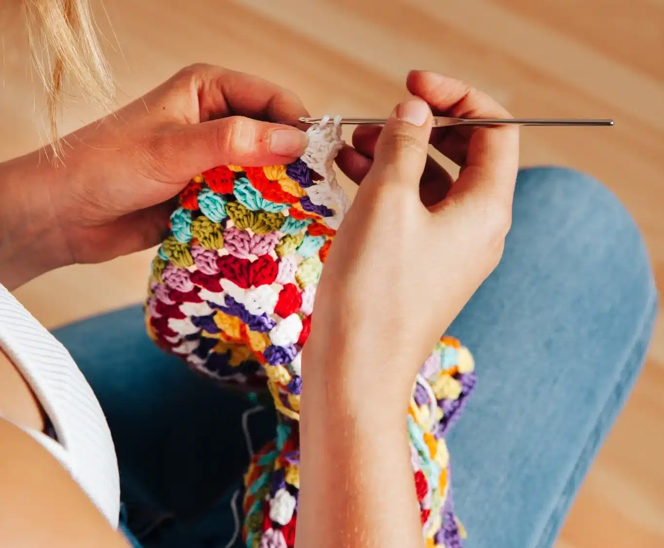 Mulher crochetando peça colorida com agulha de crochê