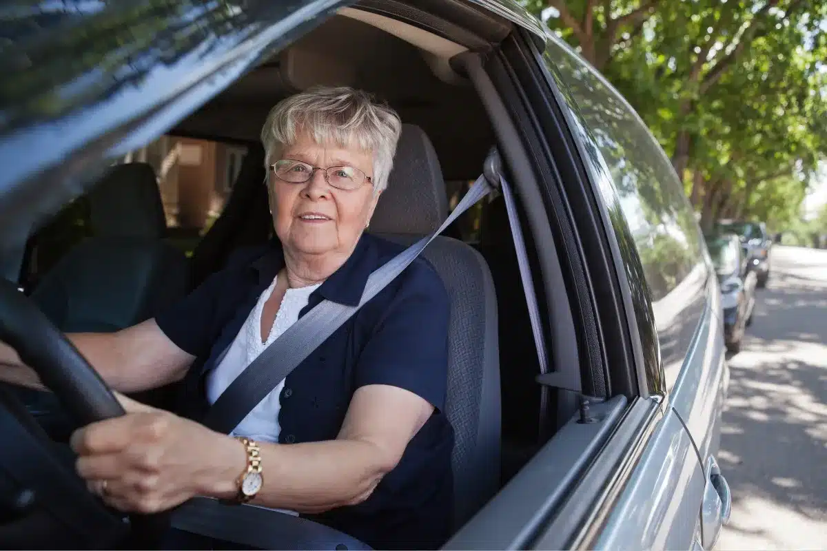 senhora dirigindo carro com cinto de segurança afivelado.
