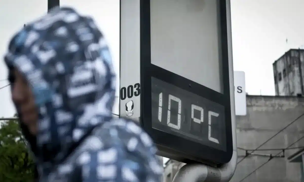 Termômetro marcando 10 graus Celsius em rua urbana no início do inverno.