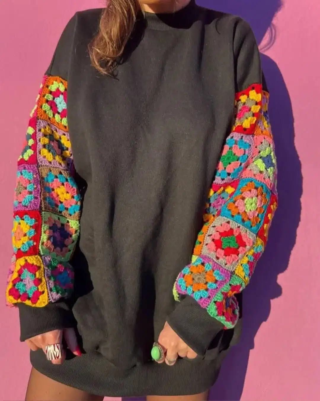 Suéter preto com mangas de crochê em quadrados coloridos.