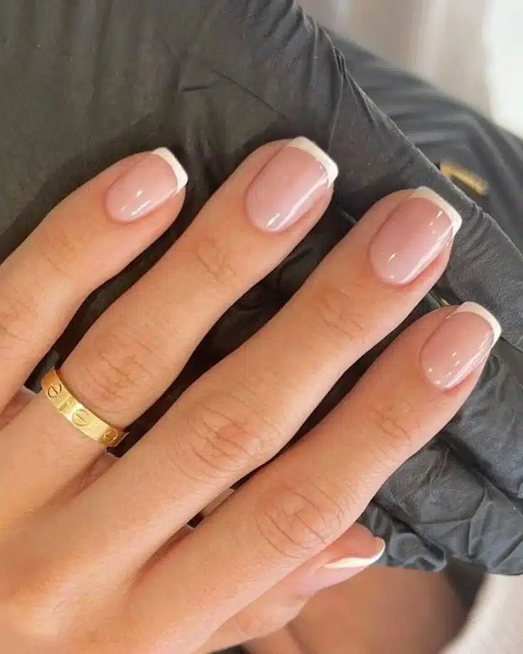 Unhas curtas com esmalte rosa claro e pontas brancas em francesinha tradicional