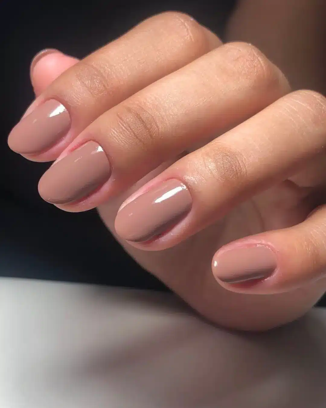 Unhas curtas com esmalte nude brilhante em tom neutro.