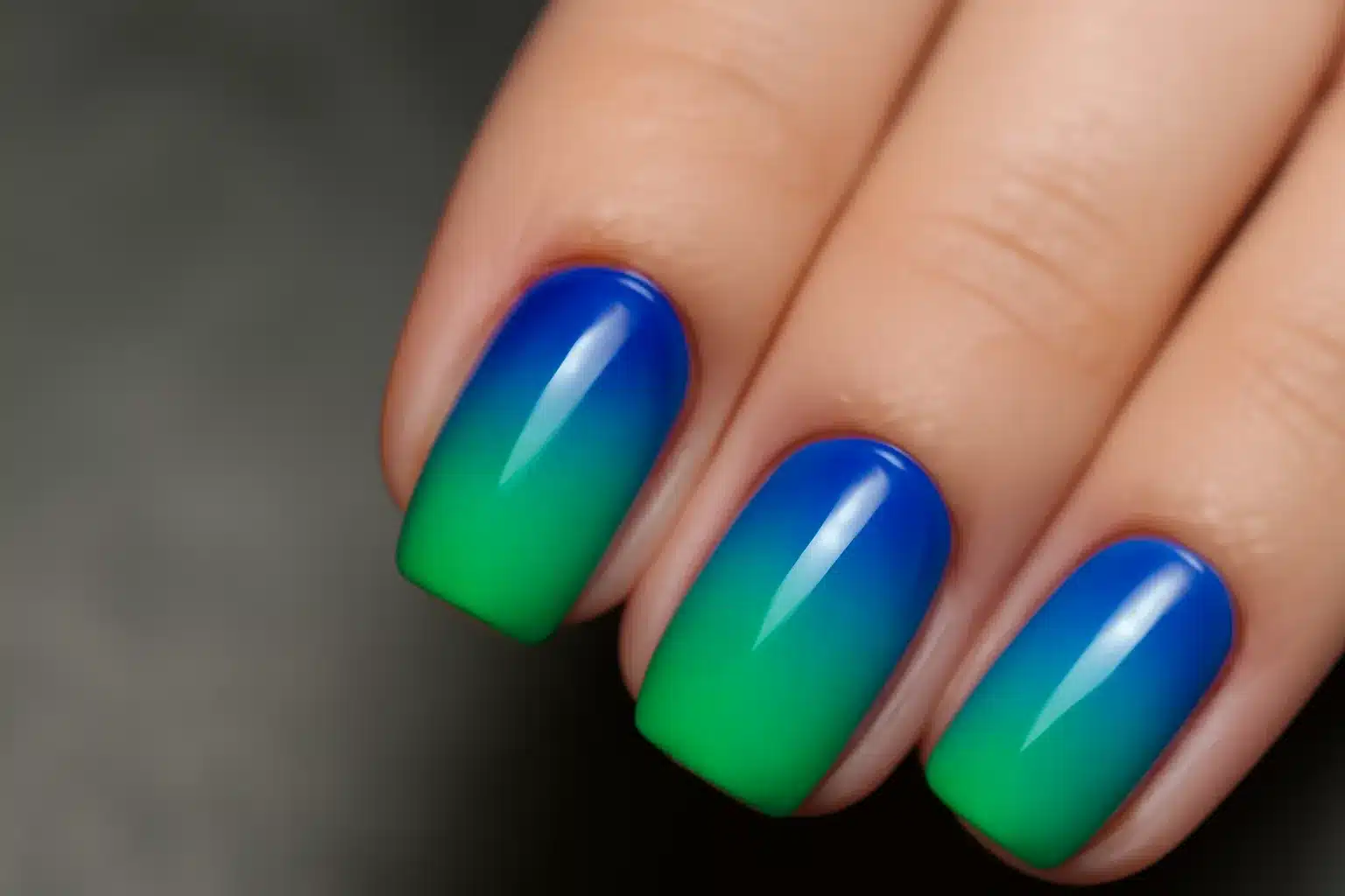 Gradiente de esmalte azul e verde em unhas bem cuidadas.
