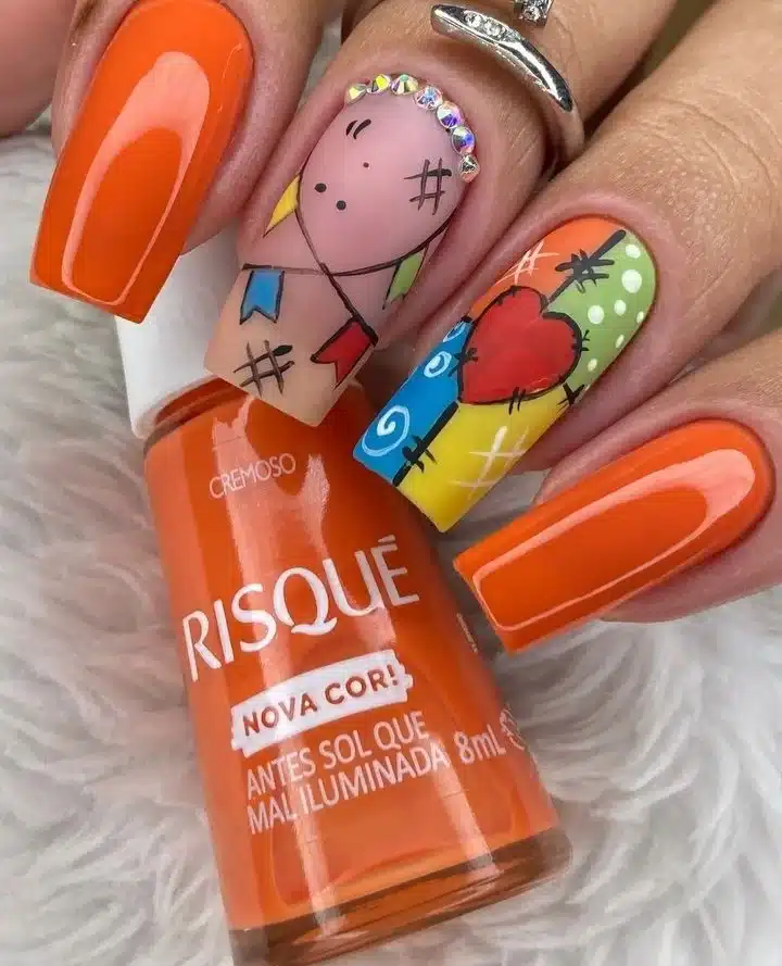 Unhas decoradas com esmalte laranja e desenhos temáticos de São João