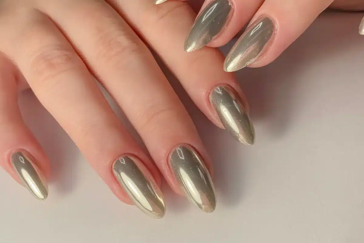 Unhas com esmaltação metalizada dourada e acabamento espelhado.