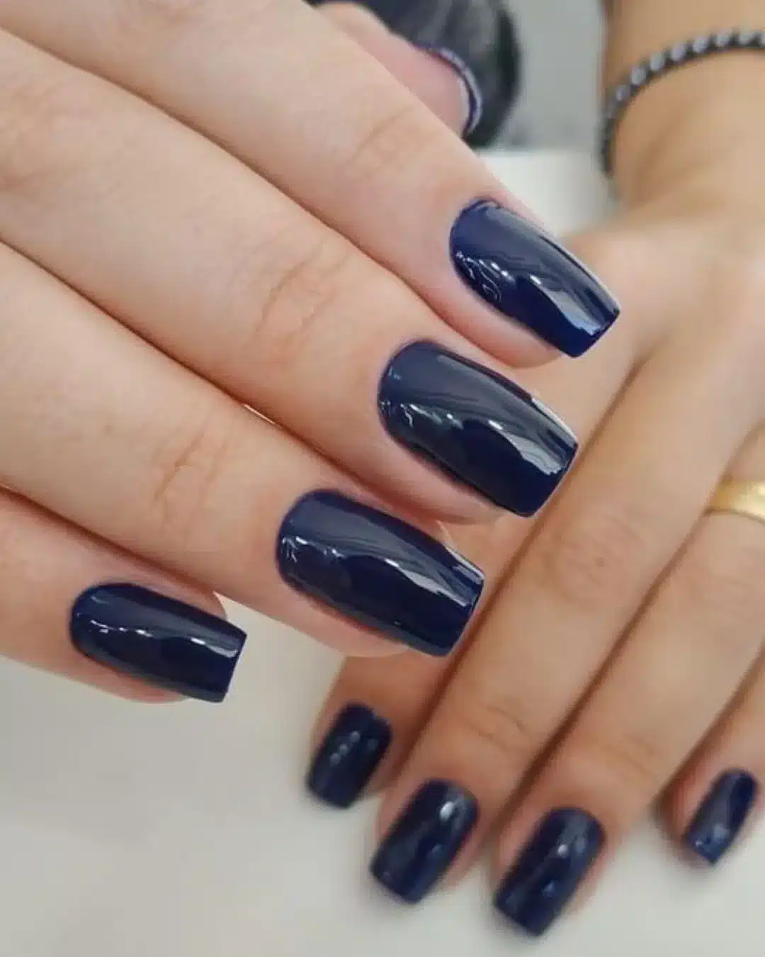 Unhas longas com esmalte azul-marinho brilhante em estilo quadrado.