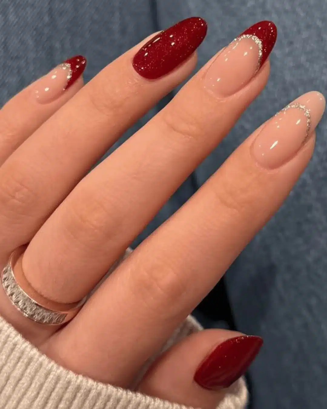 Unhas com esmalte vermelho e nude com glitter e francesinha em formato elegante.