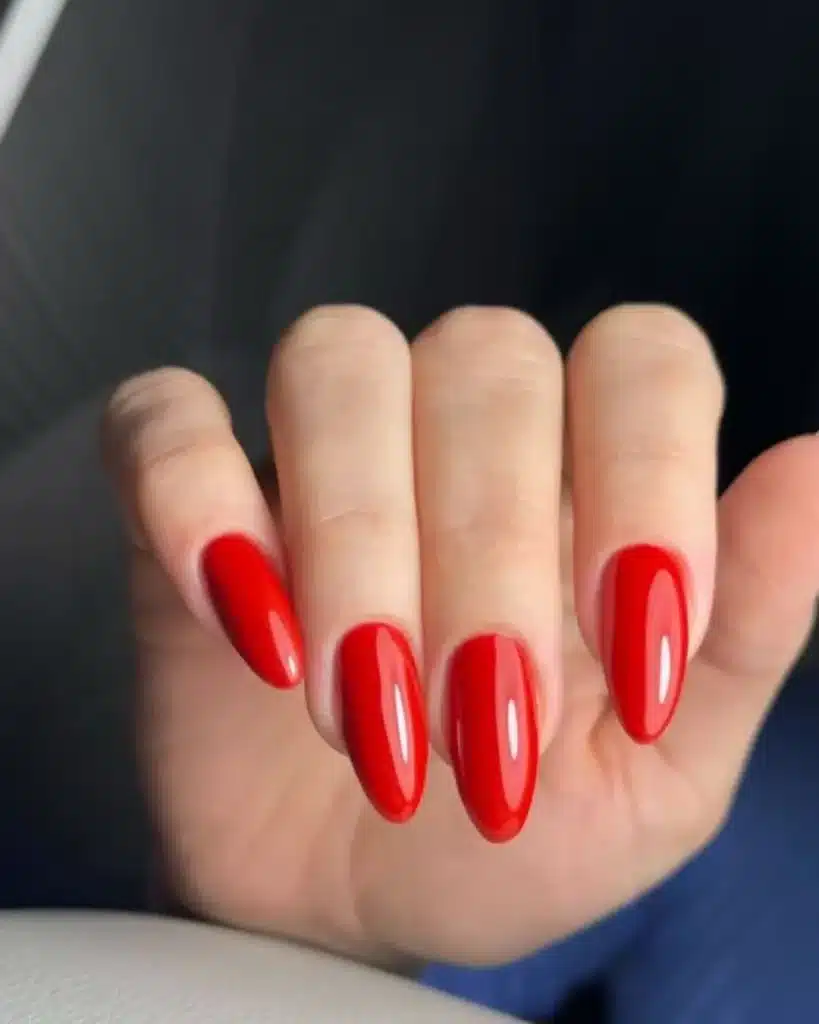 Unhas longas com esmalte vermelho vibrante e acabamento brilhante.