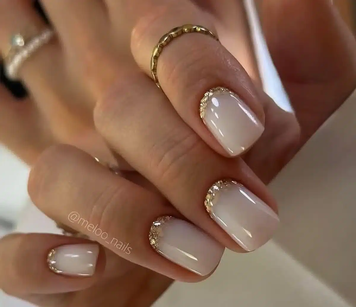 Unhas decoradas para noiva com acabamento nude e detalhes dourados na ponta, estilo elegante e sofisticado.