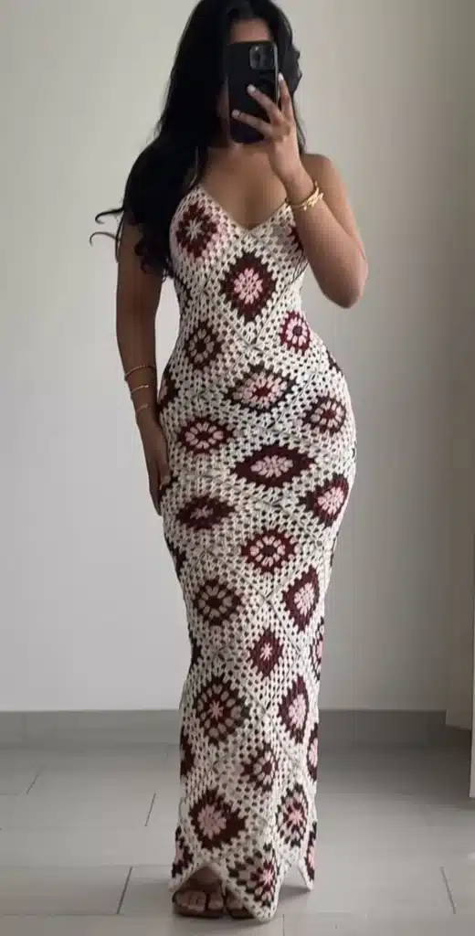 Vestido longo feito em crochê com padrão geométrico em tons de marrom e rosa.