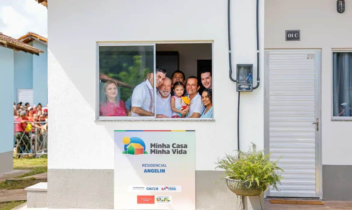 Família sorridente na janela de casa do programa Minha Casa, Minha Vida 2025