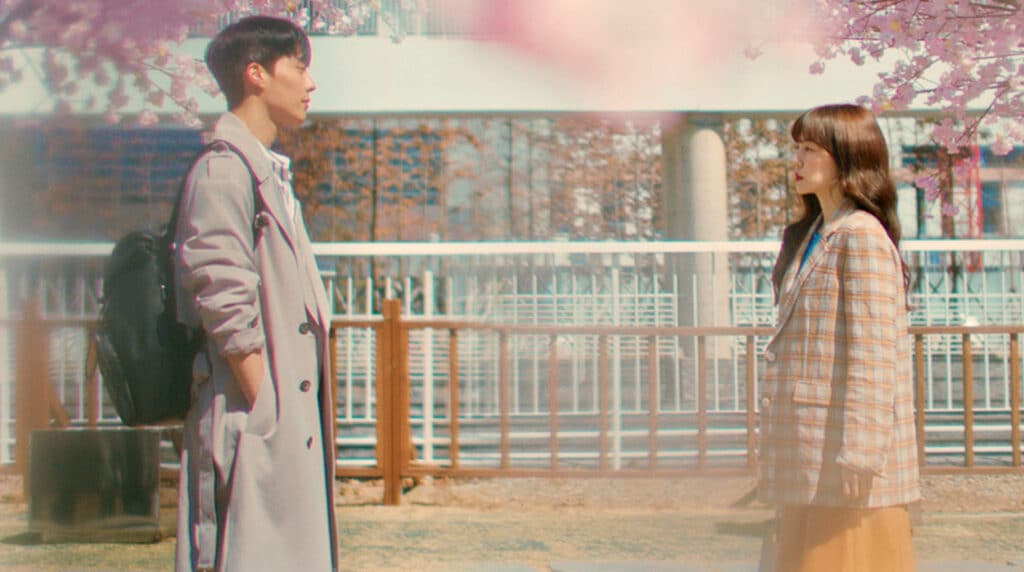 Cena de dorama com casal em momento delicado sob flores de cerejeira