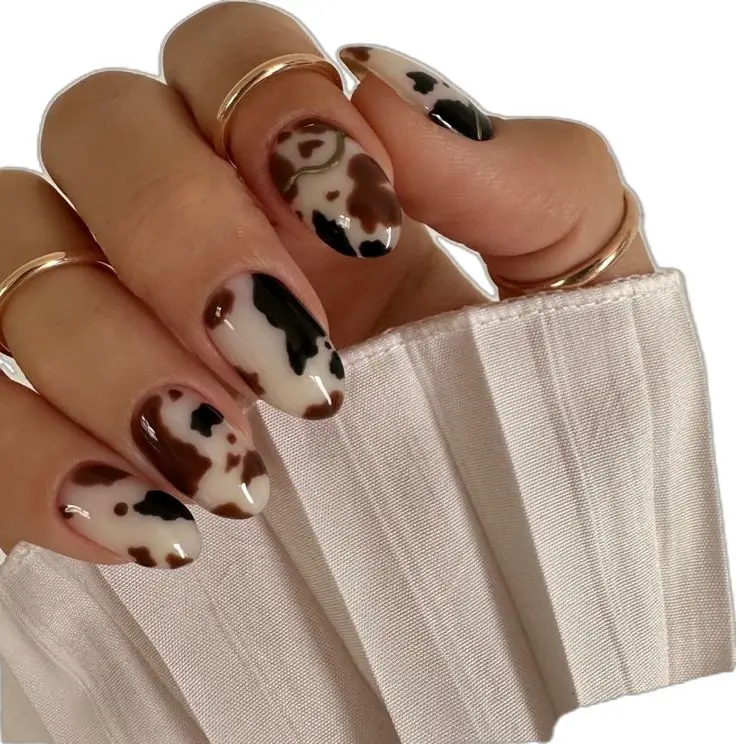 Unhas com estampa de vaca em tons de marrom e preto, tendência de animal print renovado.
