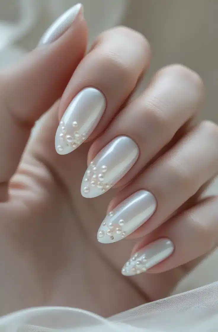 Unhas decoradas com pérolas e cristais Swarovski, criando um visual elegante e sofisticado.