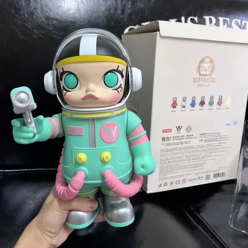 Boneca Molly da Pop Mart, com traje espacial verde e detalhes em rosa, segurando um dispositivo futurista.