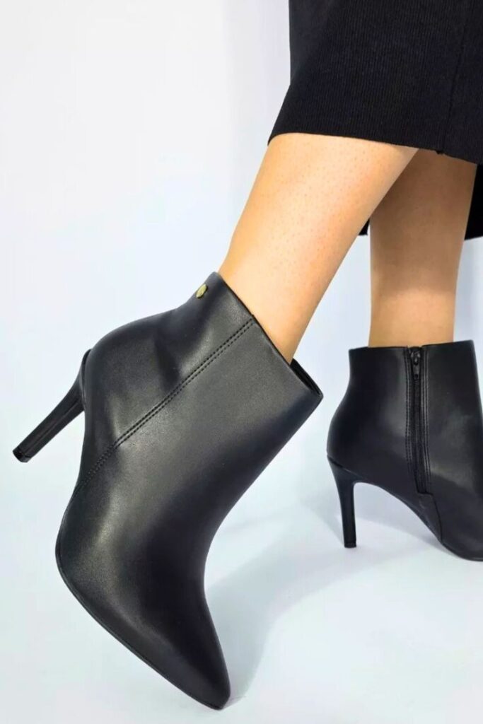 Bota feminina preta de bico fino com salto alto em look de inverno elegante