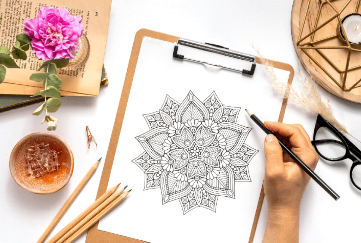 Pessoa desenhando mandala em folha com lápis grafite para atividade de relaxamento e criatividade