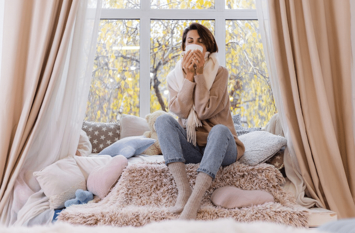 Mulher em ambiente aconchegante com cobertores e meias grossas durante o frio