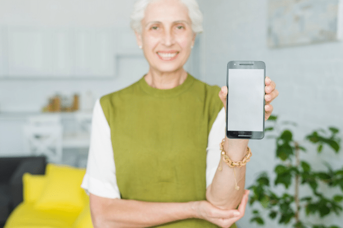 Mulher idosa segurando smartphone com a tela voltada para a câmera