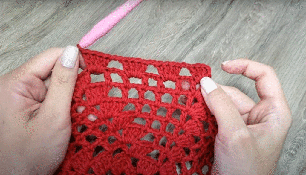Detalhe do passo a passo do crochê sendo feito com fio vermelho para centro de mesa
