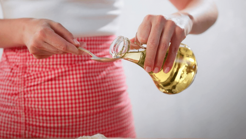 Mulher utilizando vinagre na cozinha como truque caseiro para eliminar odores