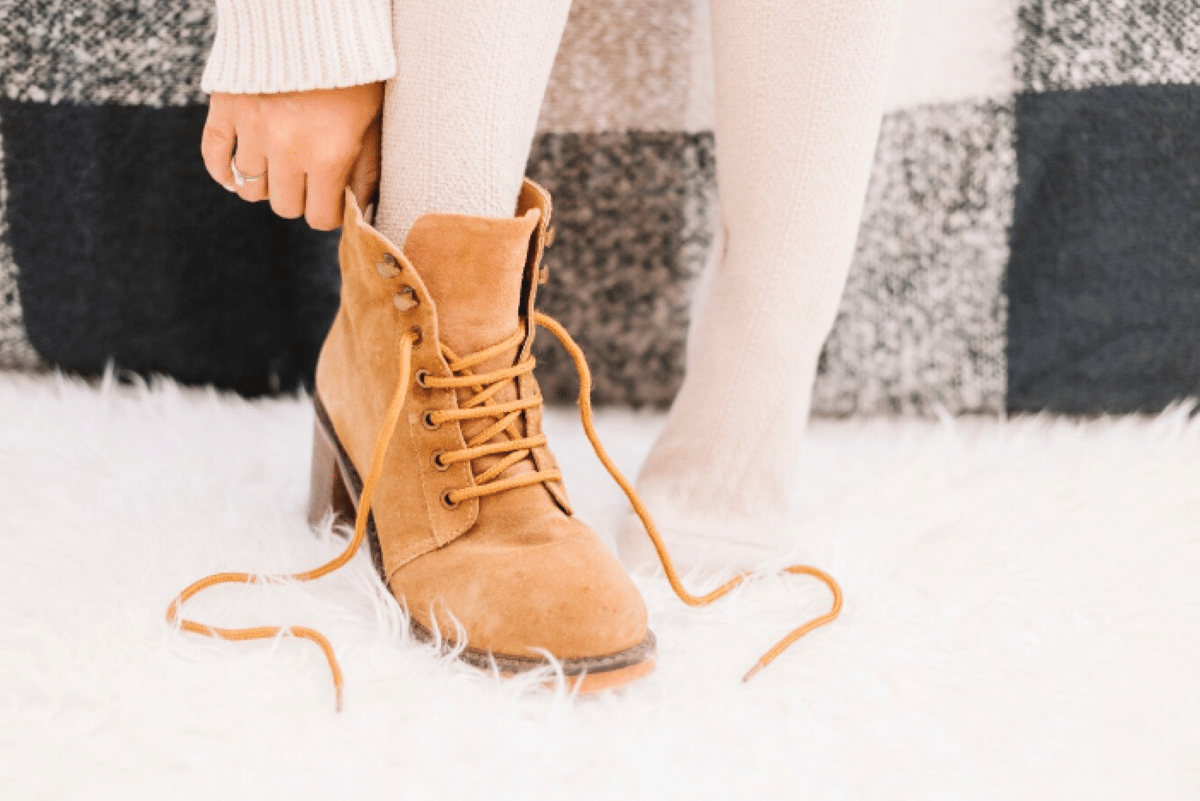 Bota de camurça caramelo com cadarço sendo calçada com meias claras