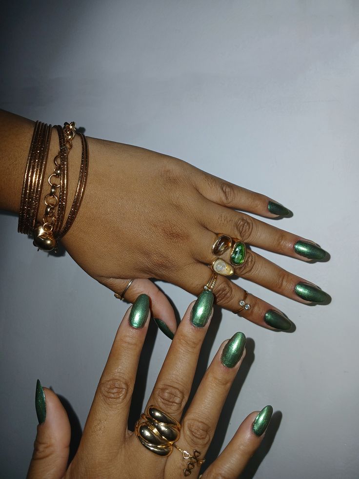 Unhas com esmalte verde metálico e acessórios dourados modernos