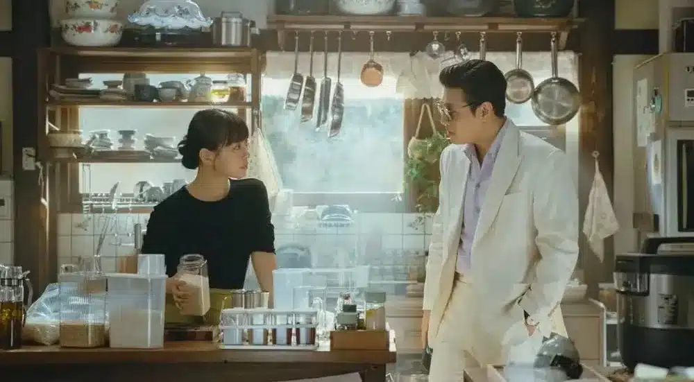 Cena do drama 'Gostinho de Amor', com Han Beom-woo e Mo Yeon-joo em um momento tenso no restaurante, misturando amor e ambição.