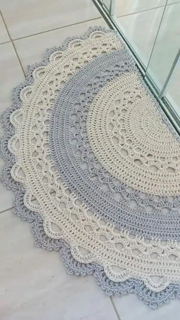 Tapete de crochê com borda trabalhada em cores suaves, bege e cinza.