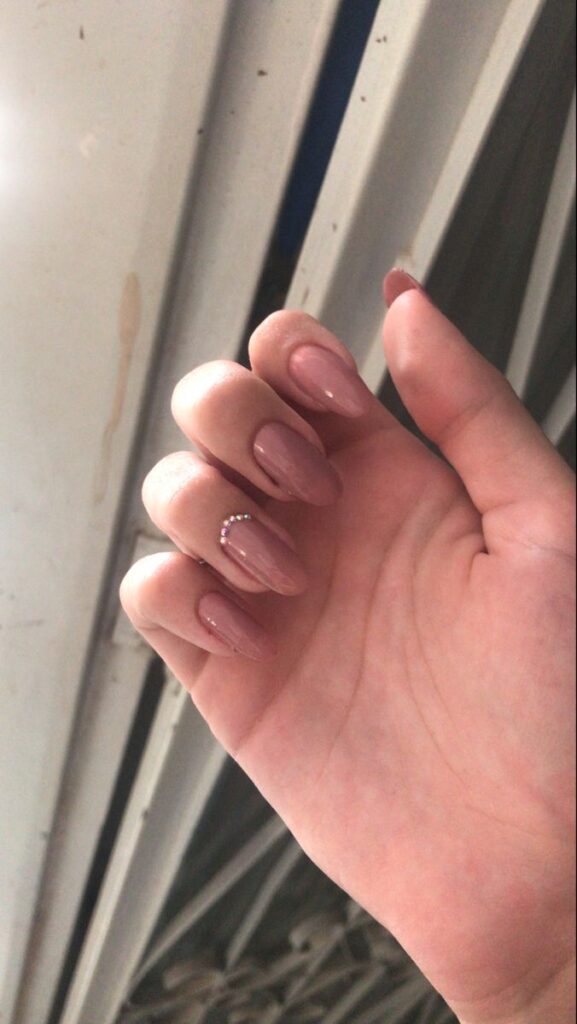 Unhas nude com acabamento brilhoso e detalhe em pedrinha decorativa
