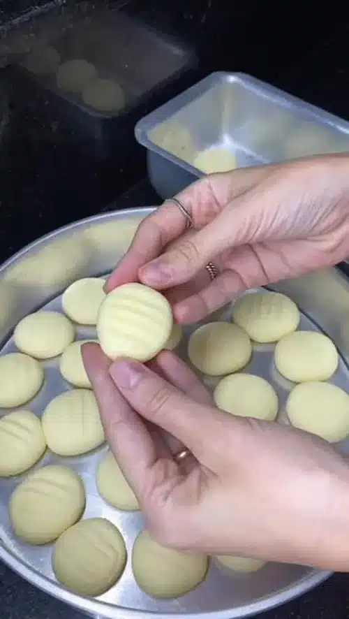 Biscoitinho caseiro pronto para ser assado, com marcações na superfície.