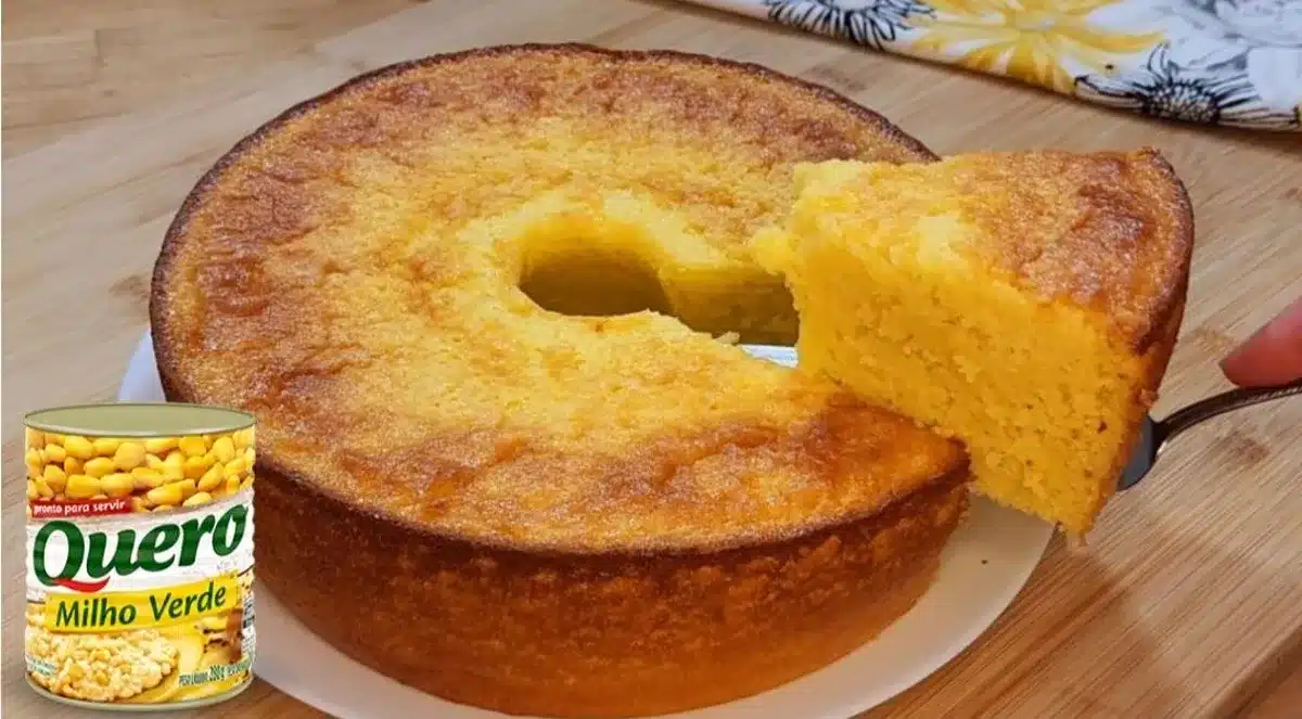 Bolo de milho de lata no liquidificador com uma fatia sendo servida, ao lado de uma lata de milho Quero.