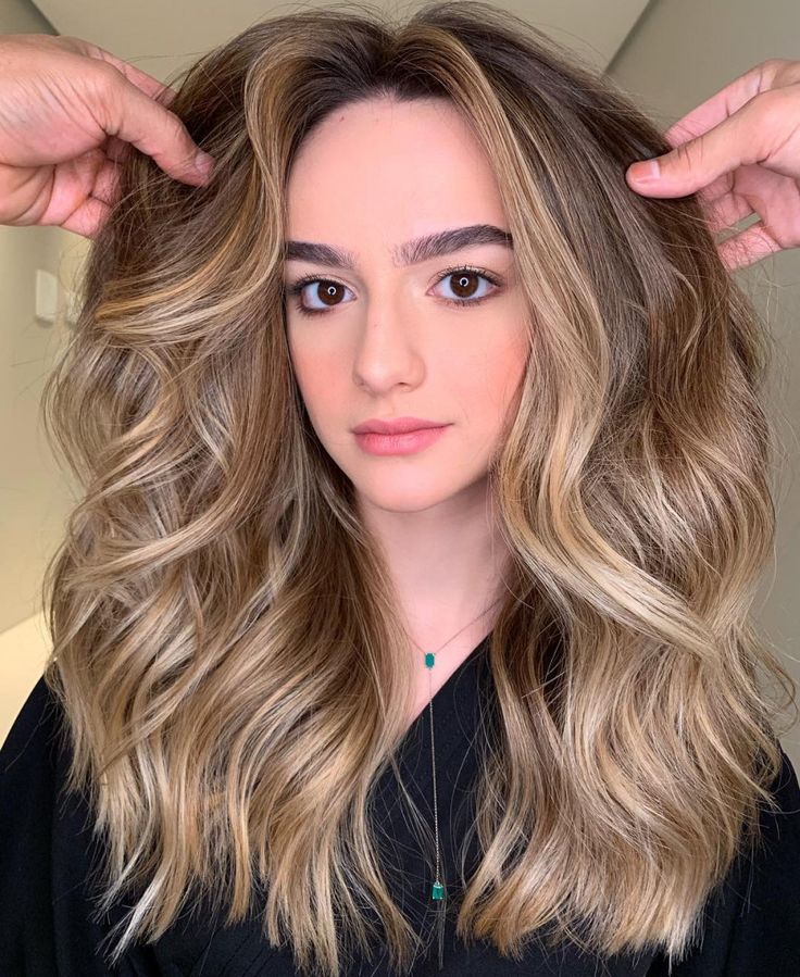 Mulher com cabelo loiro champagne ondulado e volumoso visto de frente