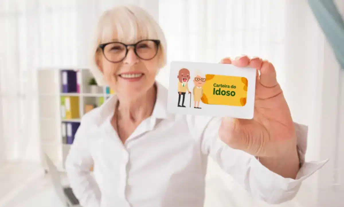 Pessoa idosa sorrindo enquanto segura uma carteira de identidade com ilustrações de personagens idosos.