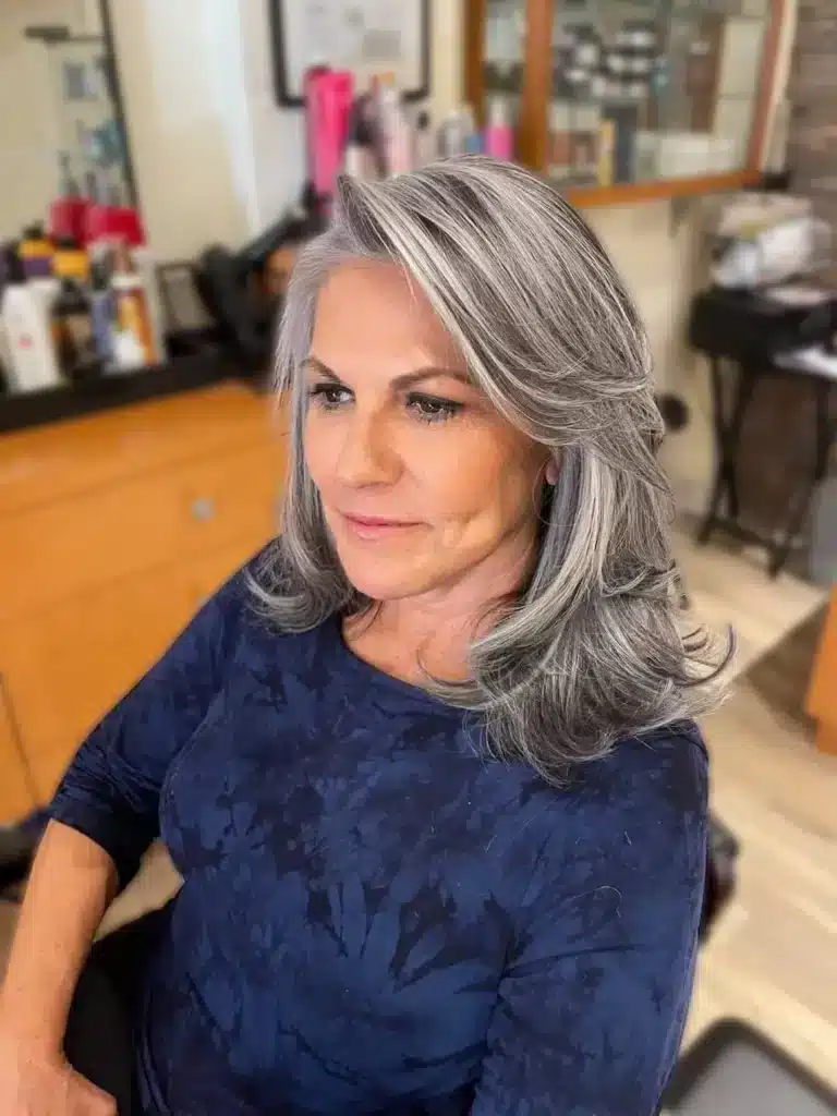 Cabelo grisalho com mechas acinzentadas e finalização em camadas suaves.