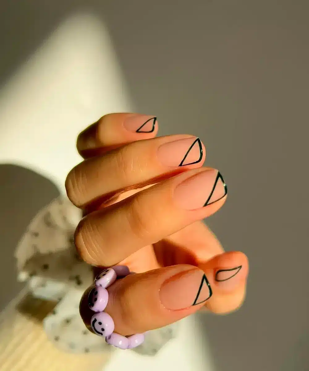 Unhas minimalistas com triângulos nas pontas, decoração elegante e moderna.