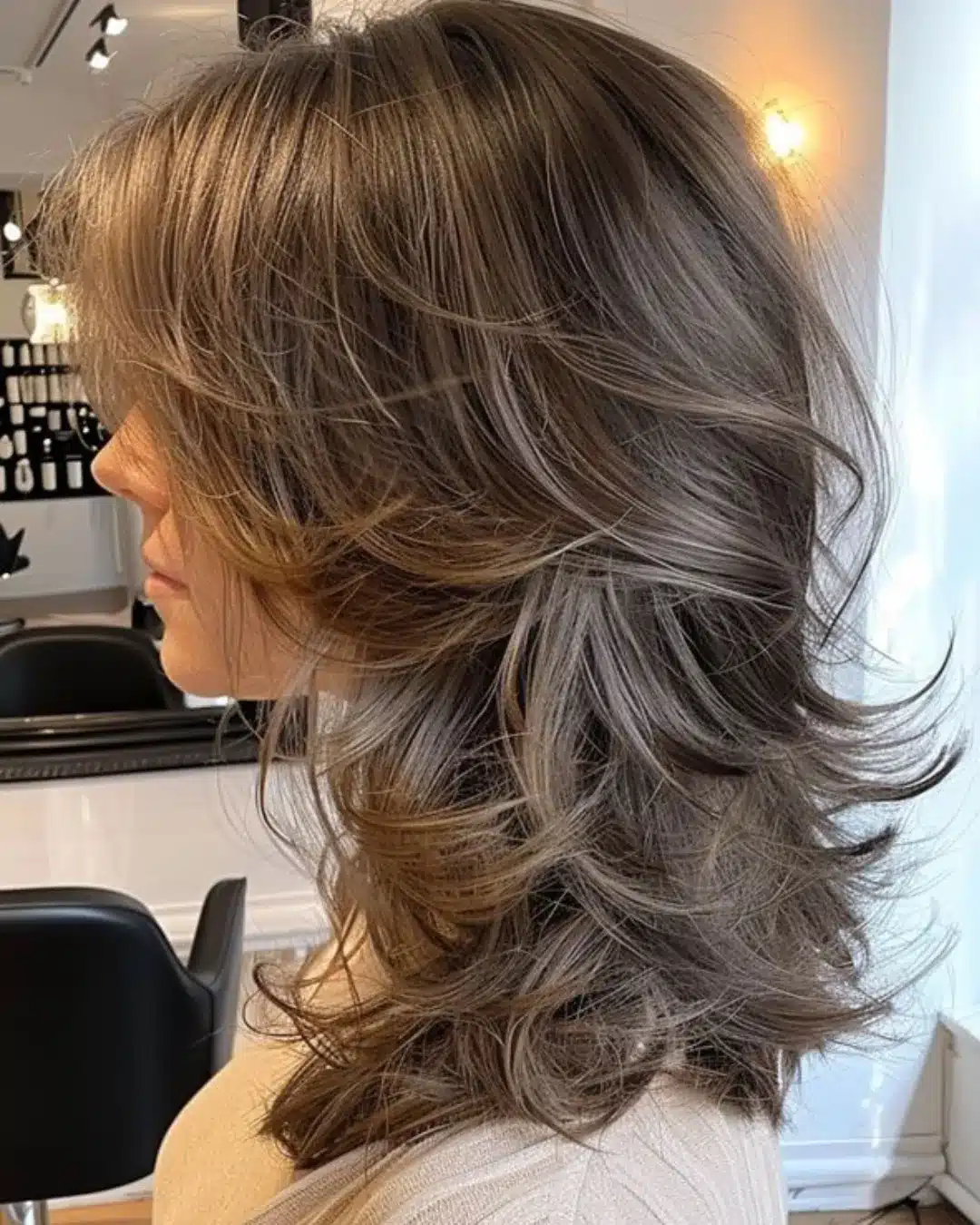 Corte em camadas longas com base reta e volume em cabelo castanho claro.